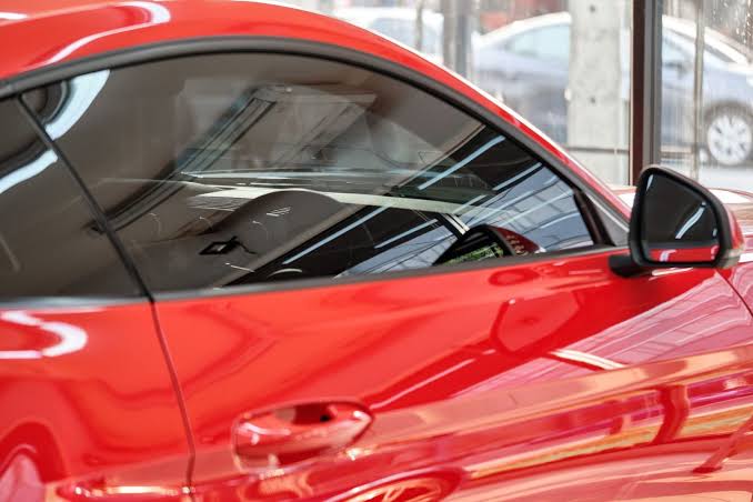 Voiture rouge en showroom chez express, vitres et rétroviseur soignés en Tarn-et-Garonne